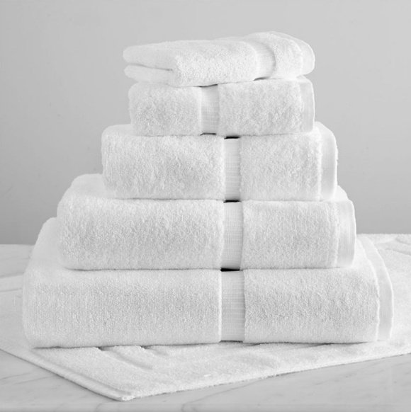 Stack of plush white cotton bath towels of graded sizes