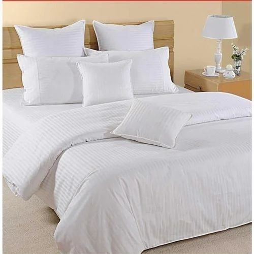 White quilted comforter styled on a bed by a window